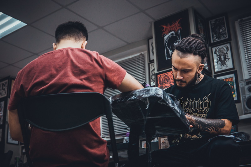 Тату-мастер за работой в оживлённой студии